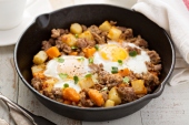 Potato and sweet potato hash with eggs in cast iron pan
